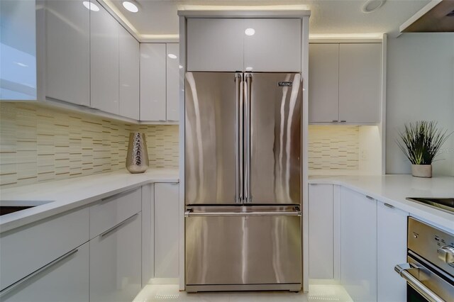 kitchen with appliances with stainless steel finishes, light tile patterned flooring, decorative backsplash, and white cabinets