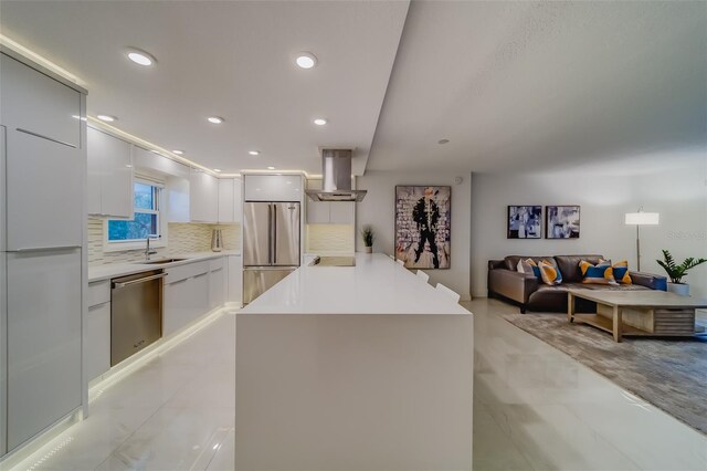 kitchen with decorative backsplash, wall chimney exhaust hood, white cabinetry, sink, and stainless steel appliances