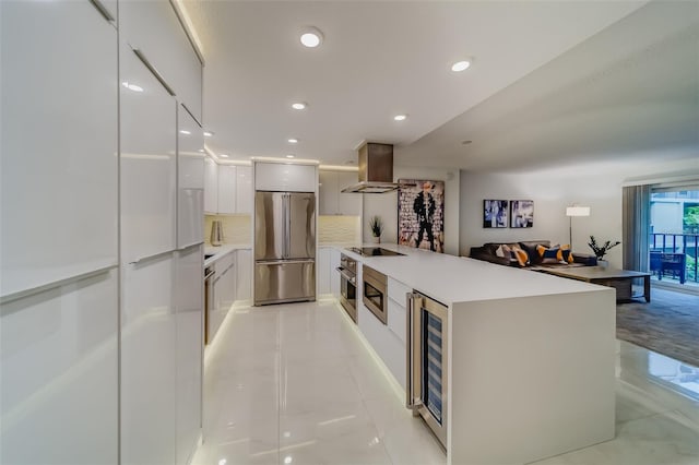 kitchen featuring light tile patterned flooring, appliances with stainless steel finishes, wall chimney exhaust hood, decorative backsplash, and beverage cooler