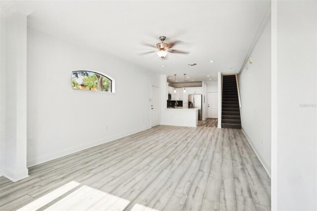 unfurnished living room featuring sink, ceiling fan, and light wood-type flooring