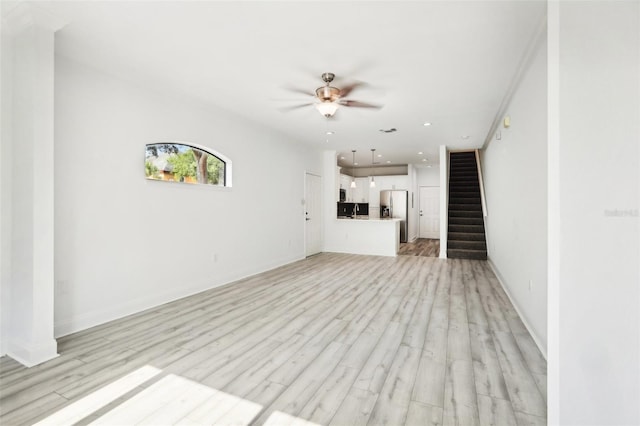 unfurnished living room featuring ceiling fan, recessed lighting, a sink, stairway, and light wood-type flooring