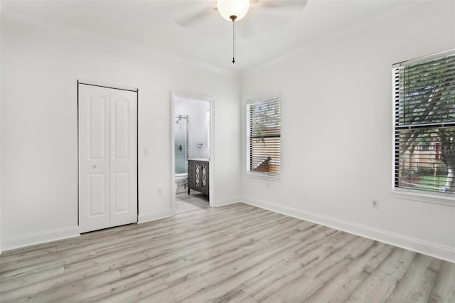 unfurnished bedroom with ensuite bath, light wood-style flooring, baseboards, and a closet