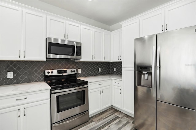 kitchen featuring white cabinets, light wood-style floors, stainless steel appliances, and decorative backsplash