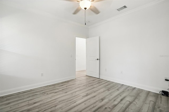 unfurnished room featuring wood finished floors, a ceiling fan, visible vents, baseboards, and ornamental molding