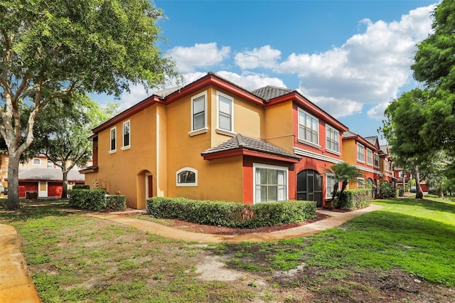 view of side of property with stucco siding and a lawn