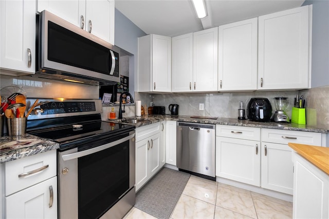 kitchen with light tile patterned flooring, appliances with stainless steel finishes, backsplash, and white cabinetry