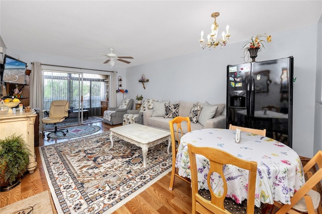 dining area with ceiling fan with notable chandelier and light hardwood / wood-style flooring