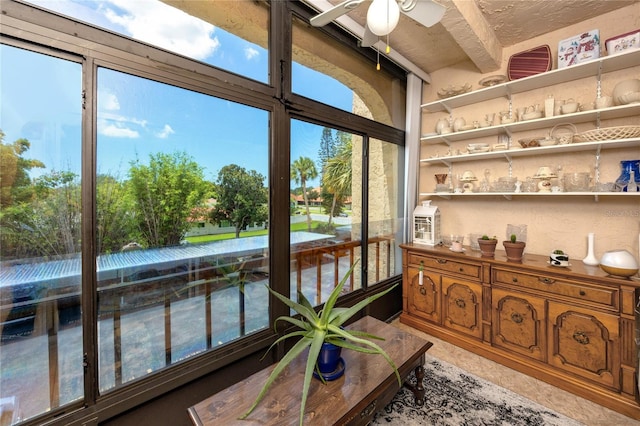 sunroom / solarium with beamed ceiling, a healthy amount of sunlight, and ceiling fan