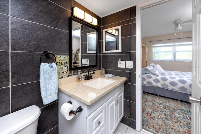 bathroom with vanity, tile patterned floors, ceiling fan, tile walls, and toilet