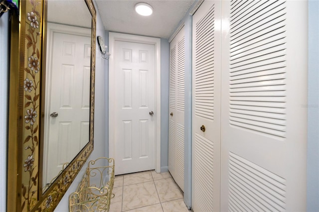 corridor with a textured ceiling and light tile patterned floors