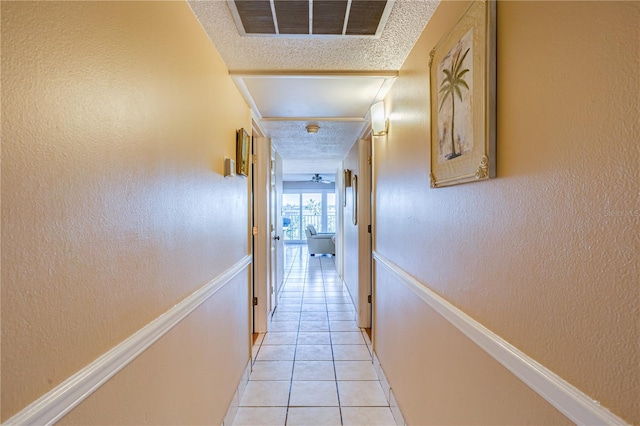 corridor featuring light tile patterned flooring and a textured ceiling