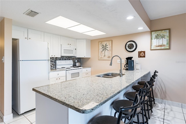 kitchen featuring sink, white appliances, a kitchen breakfast bar, white cabinets, and kitchen peninsula