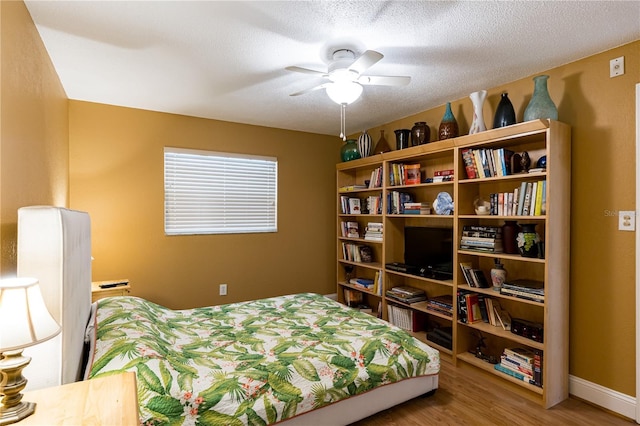 bedroom with hardwood / wood-style flooring, a textured ceiling, and ceiling fan