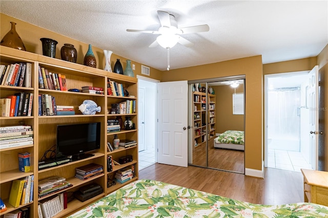 bedroom with a textured ceiling, a closet, ceiling fan, and light wood-type flooring