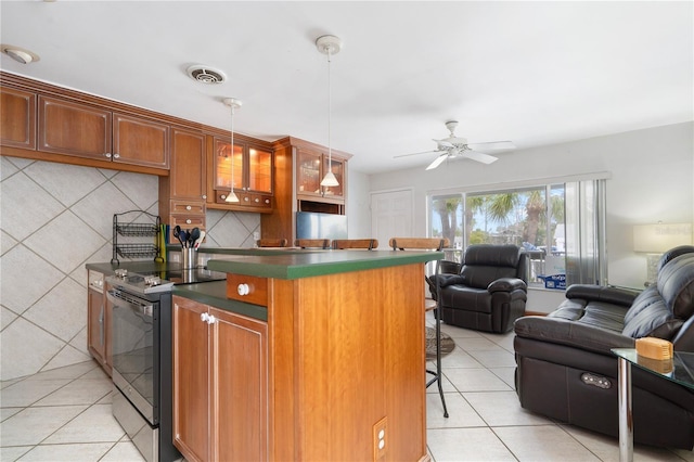 kitchen featuring light tile patterned floors, ceiling fan, range with electric cooktop, a kitchen bar, and decorative backsplash