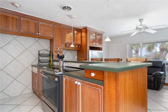 kitchen featuring stainless steel electric range oven, pendant lighting, tasteful backsplash, light tile patterned floors, and ceiling fan