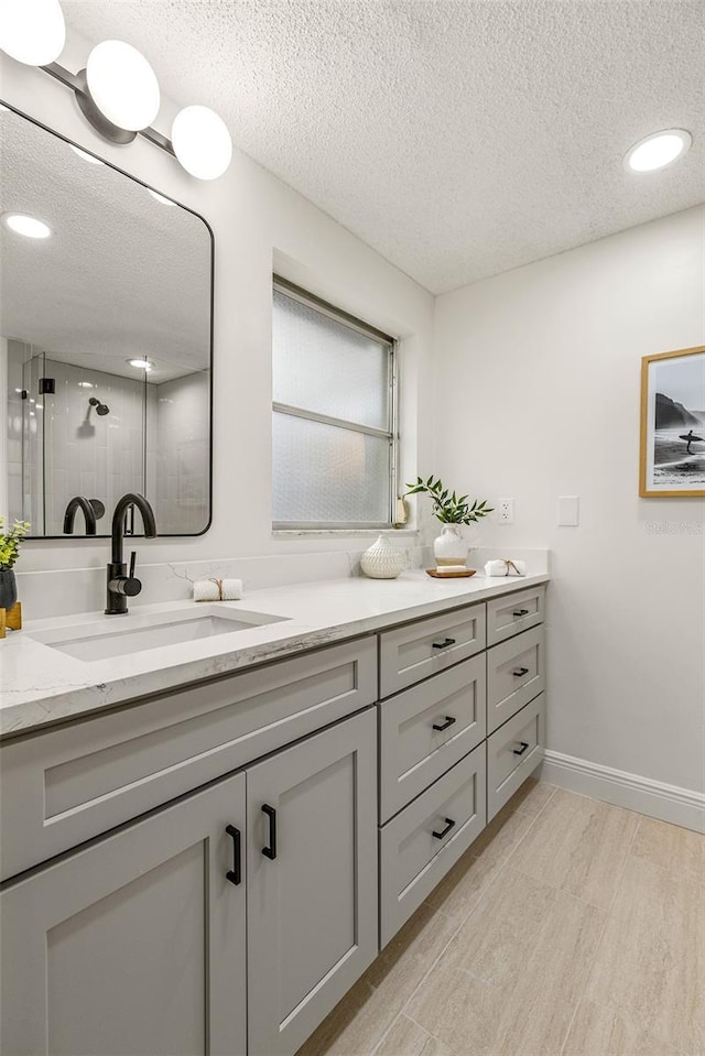 bathroom featuring walk in shower, vanity, wood-type flooring, and a textured ceiling