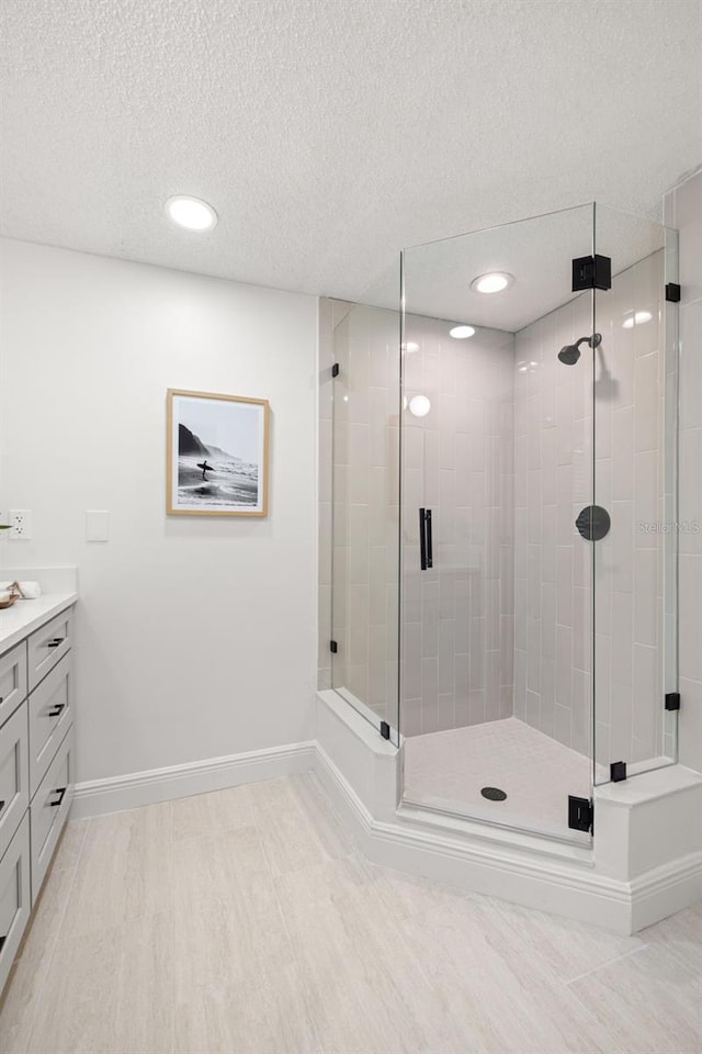 bathroom with a textured ceiling, an enclosed shower, and vanity