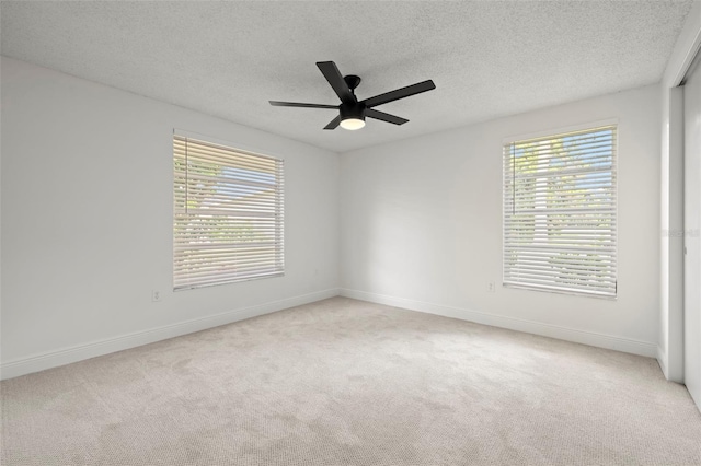 carpeted spare room with a textured ceiling, ceiling fan, and plenty of natural light