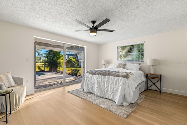 bedroom with a textured ceiling, ceiling fan, hardwood / wood-style flooring, and access to outside