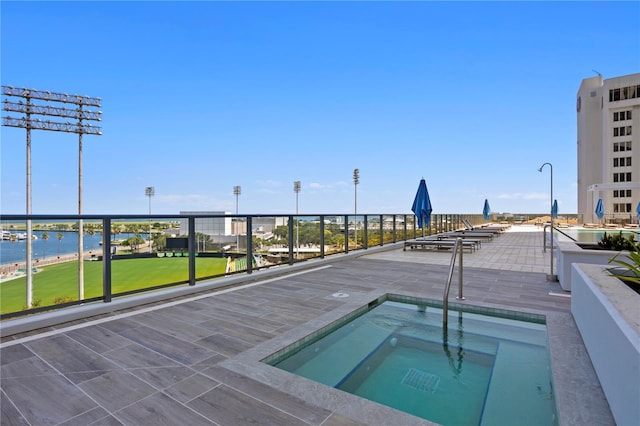 view of swimming pool featuring a water view and a hot tub