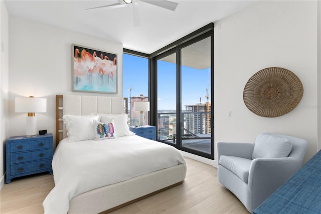 bedroom with expansive windows, access to exterior, ceiling fan, and light hardwood / wood-style flooring