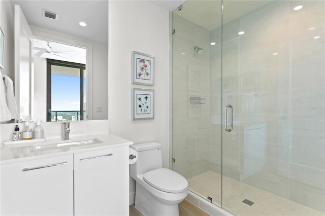 bathroom with walk in shower, ceiling fan, vanity, and toilet