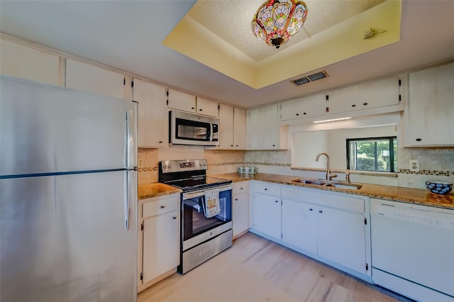 kitchen featuring stainless steel appliances, light hardwood / wood-style floors, light stone counters, and sink