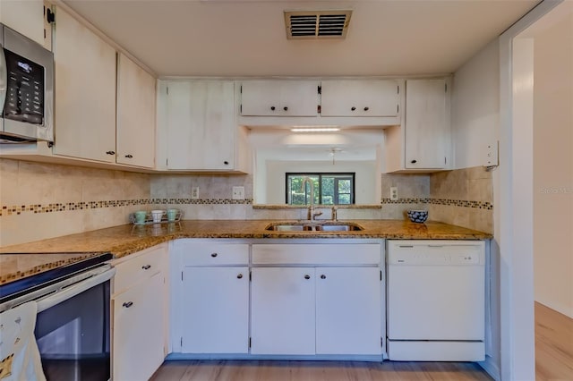 kitchen with white cabinetry, decorative backsplash, sink, white dishwasher, and light hardwood / wood-style flooring