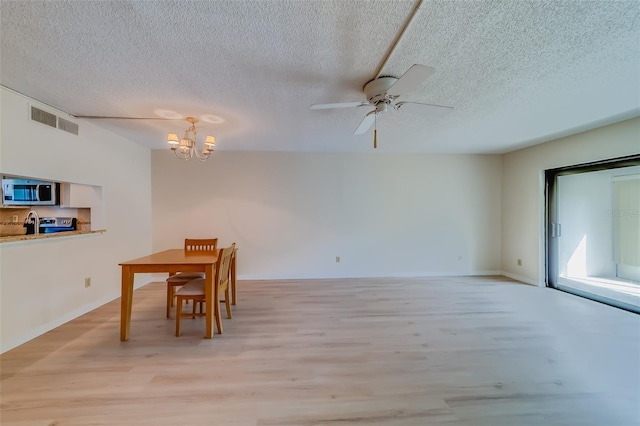 dining room with ceiling fan with notable chandelier, a textured ceiling, and light hardwood / wood-style flooring