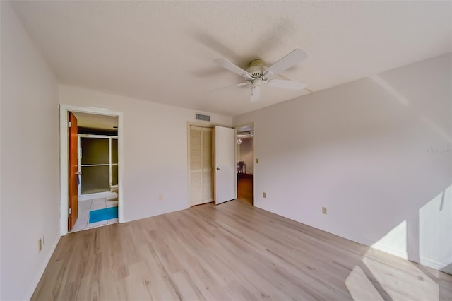 unfurnished bedroom with a closet, ensuite bathroom, ceiling fan, and light wood-type flooring