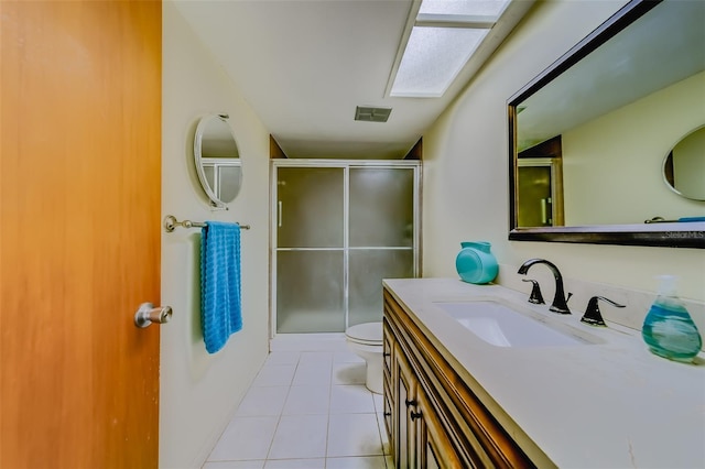 bathroom with tile patterned floors, toilet, vanity, and an enclosed shower