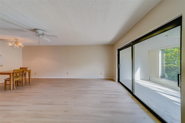 interior space with a textured ceiling, ceiling fan with notable chandelier, and light wood-type flooring