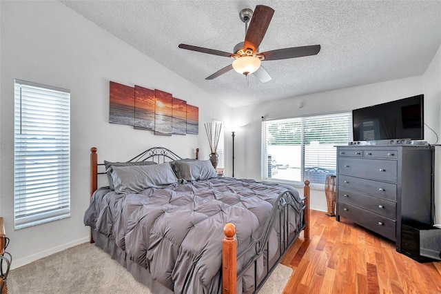 bedroom with a textured ceiling, ceiling fan, light wood-type flooring, and lofted ceiling