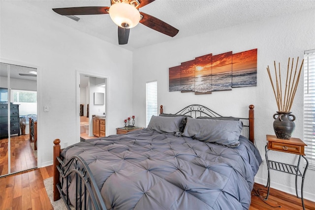 bedroom featuring ensuite bathroom, a textured ceiling, ceiling fan, and wood-type flooring