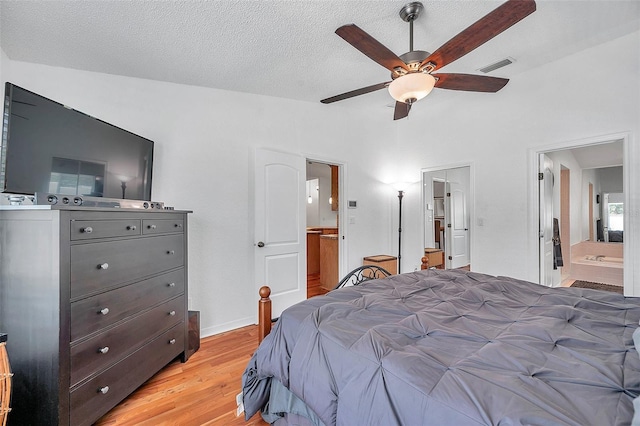 bedroom featuring a textured ceiling, light hardwood / wood-style flooring, ensuite bath, and ceiling fan