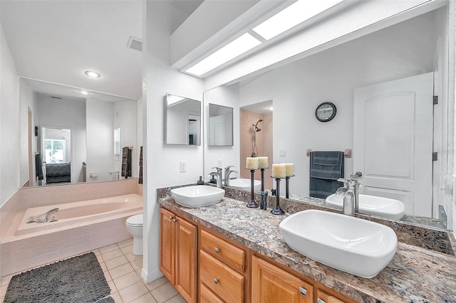 bathroom with tiled bath, tile patterned floors, toilet, and dual bowl vanity