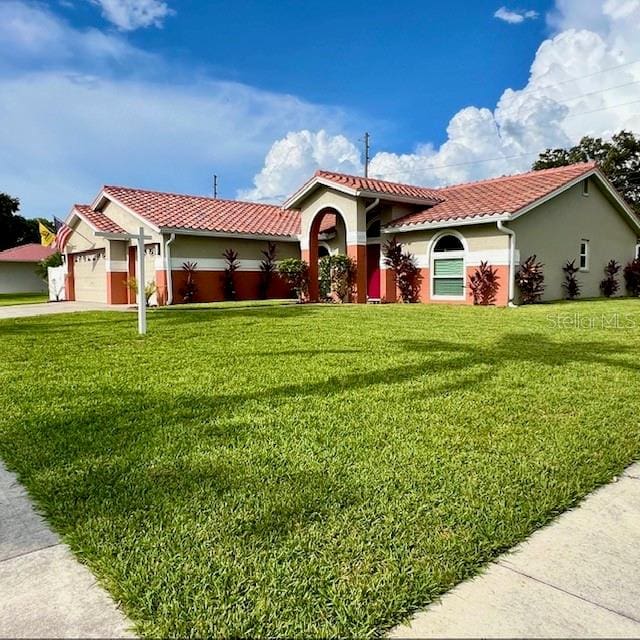 mediterranean / spanish house featuring a garage and a front lawn