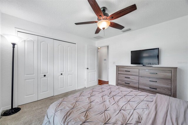 carpeted bedroom featuring a textured ceiling, a closet, and ceiling fan