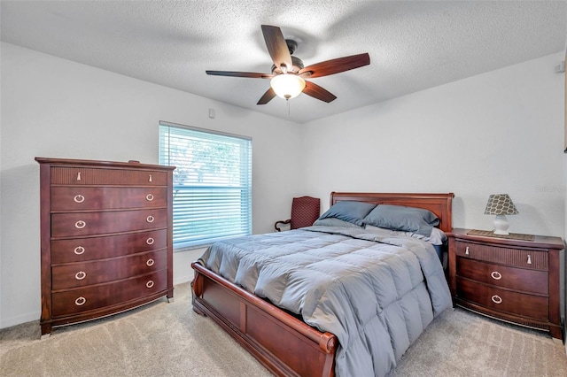 bedroom with a textured ceiling, light colored carpet, and ceiling fan