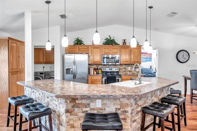 kitchen featuring stainless steel appliances, a breakfast bar, light wood-type flooring, lofted ceiling, and a large island