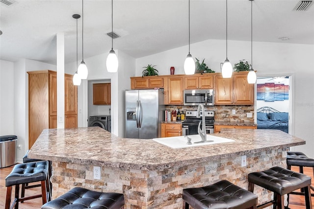 kitchen featuring stainless steel appliances, decorative backsplash, light hardwood / wood-style floors, a kitchen breakfast bar, and a spacious island