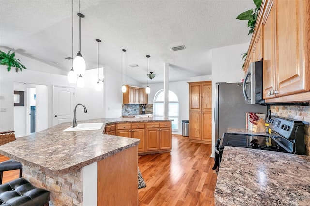 kitchen featuring a breakfast bar area, tasteful backsplash, sink, light wood-type flooring, and lofted ceiling