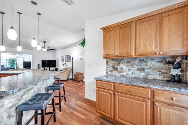 kitchen featuring lofted ceiling, tasteful backsplash, light wood-type flooring, ceiling fan, and pendant lighting