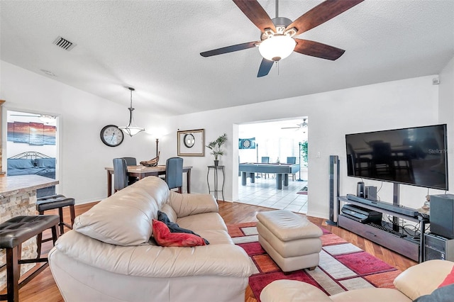 living room featuring light hardwood / wood-style floors, a textured ceiling, and ceiling fan