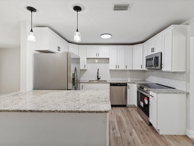 kitchen featuring sink, white cabinetry, hanging light fixtures, stainless steel appliances, and backsplash