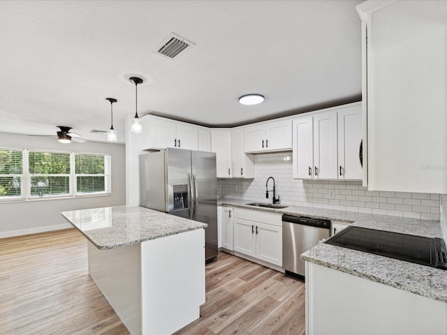 kitchen featuring sink, hanging light fixtures, appliances with stainless steel finishes, white cabinets, and backsplash