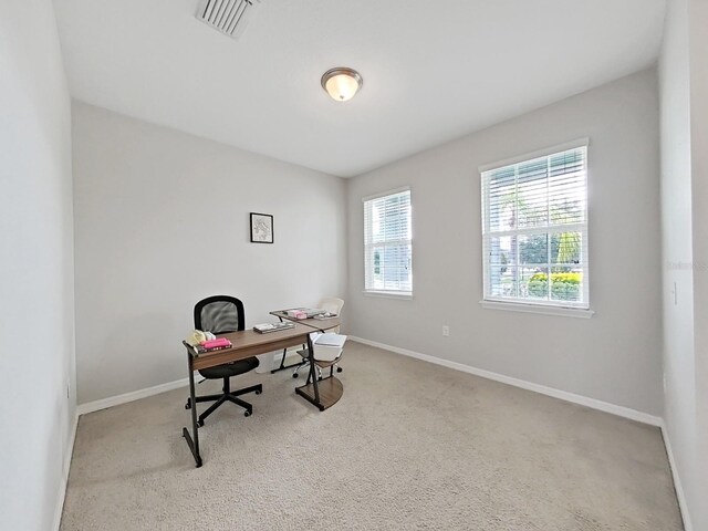 office area with baseboards, visible vents, and light colored carpet