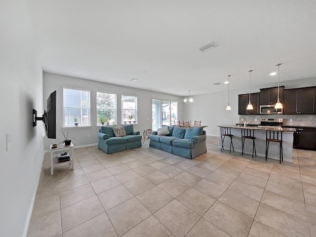 living area with light tile patterned floors, a chandelier, and baseboards