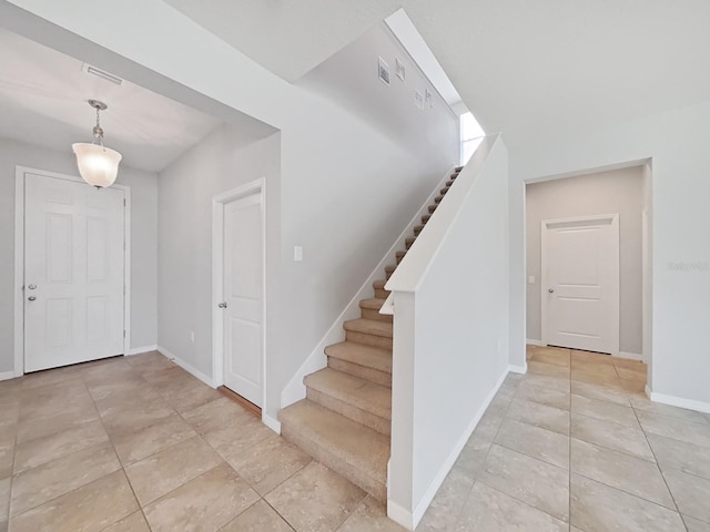 entrance foyer with visible vents, stairway, baseboards, and light tile patterned flooring